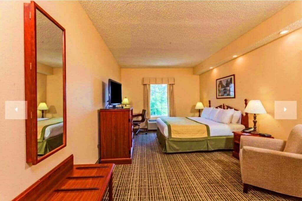 Une chambre d’hôtel avec un lit, un bureau, une chaise, une télévision et une fenêtre.