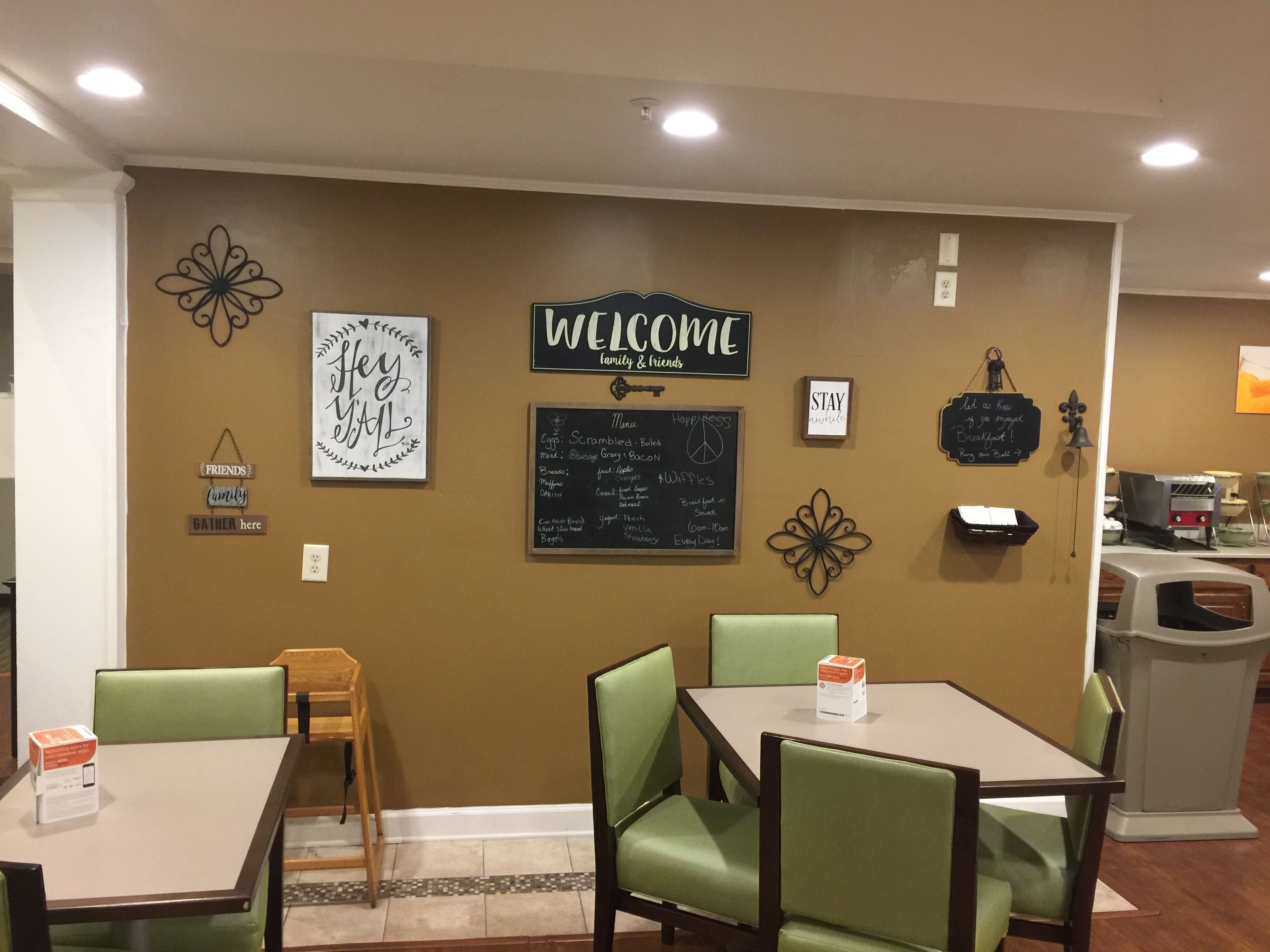 A cafe interior with tables and chairs, a welcome sign, and a chalkboard menu.