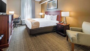 A hotel room with a large bed, a desk with a computer, a chair, a desk lamp, and a telephone. - Quality Inn Palm Bay - Melbourne I-95 (Palm Bay)