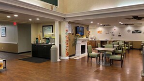 A hotel lobby with a reception desk, a fireplace, and a dining area with tables and chairs. - Quality Inn Palm Bay - Melbourne I-95 (Palm Bay)