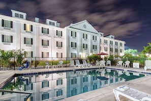 A hotel with a swimming pool, lounge chairs, and a covered area with umbrellas. - Quality Inn Palm Bay - Melbourne I-95 (Palm Bay)