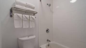 A bathroom with a toilet, a bathtub, and a towel rack with folded towels.