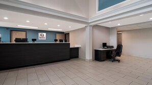A reception area with a dark reception desk, a 'Quality' sign, a computer, and a black office chair. - Quality Inn Goldsboro (Goldsboro)