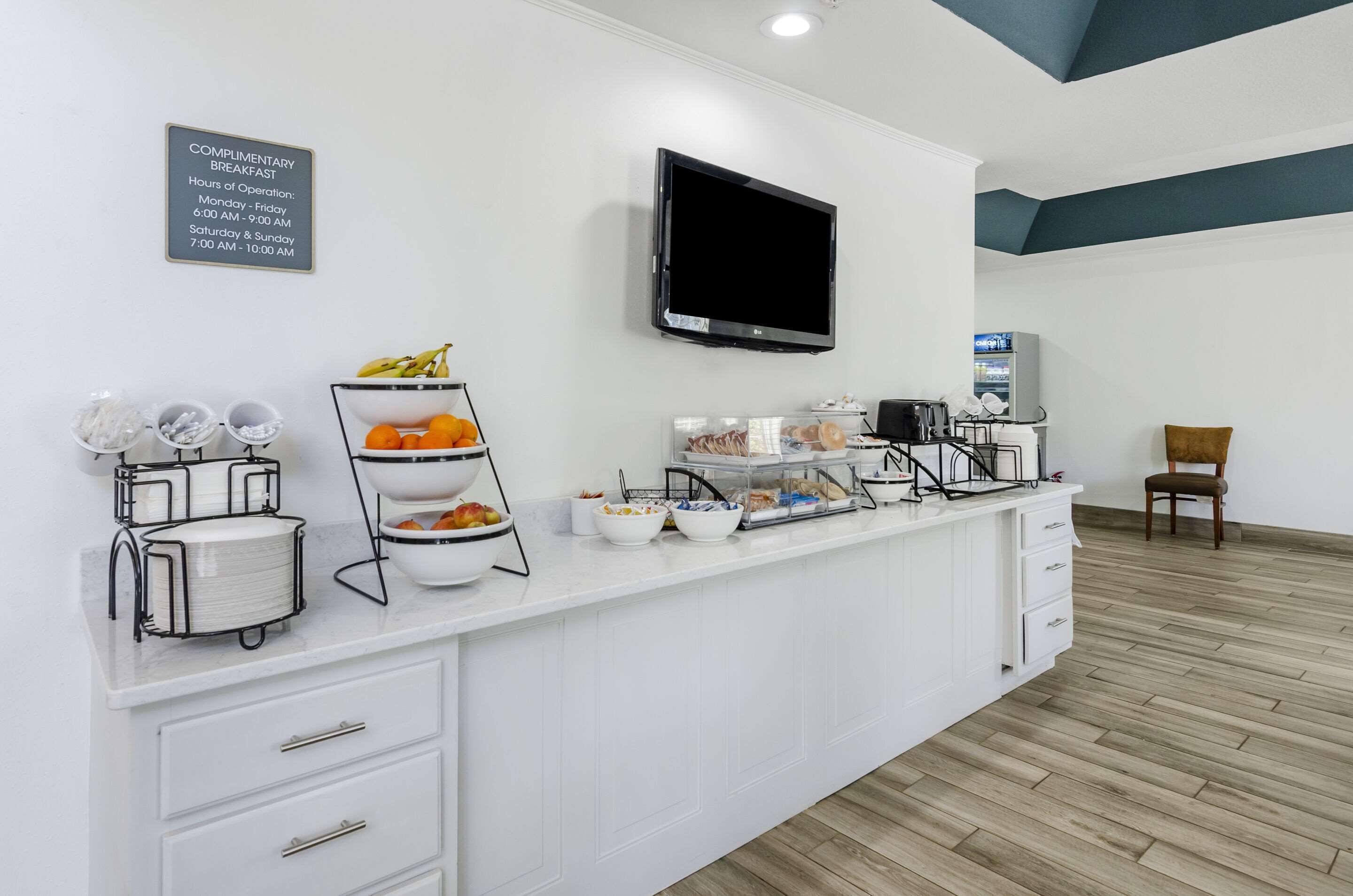 A breakfast bar with a complimentary breakfast sign, a flat-screen TV, and a microwave.