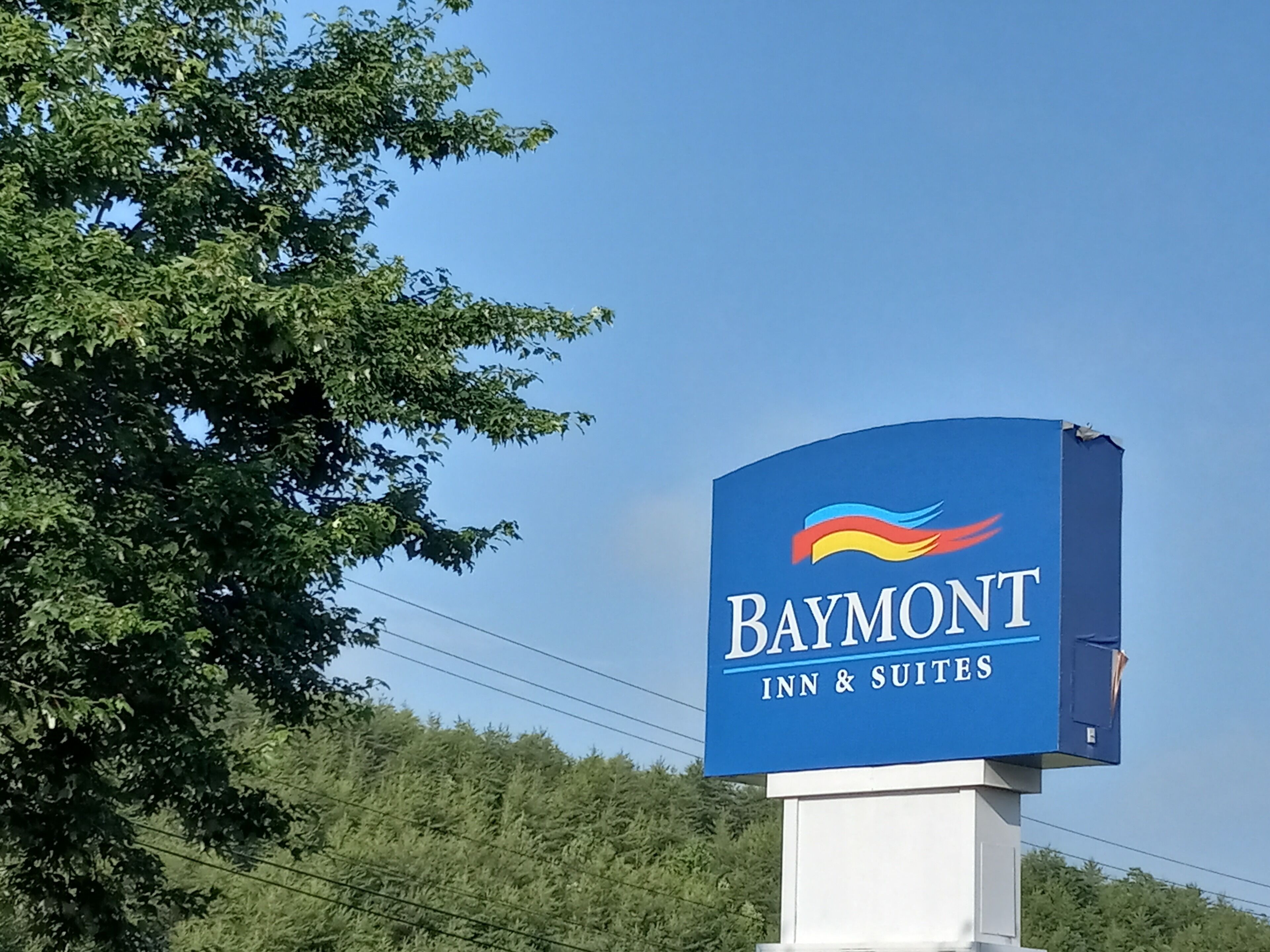 Een Baymont Inn & Suites bord met een blauwe achtergrond en een logo van een kleurrijke vlam.