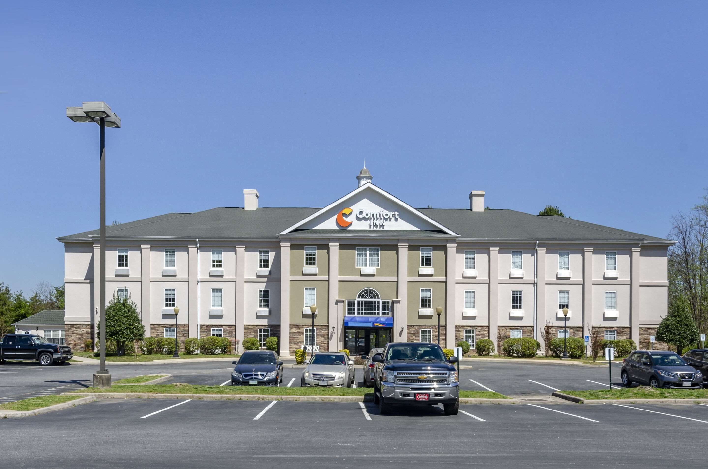 A Comfort Inn hotel with a parking lot and several cars parked in front.