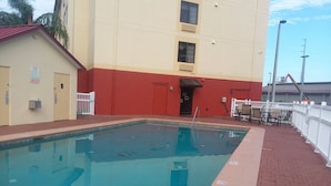 Una piscina con un edificio rojo y amarillo al fondo.