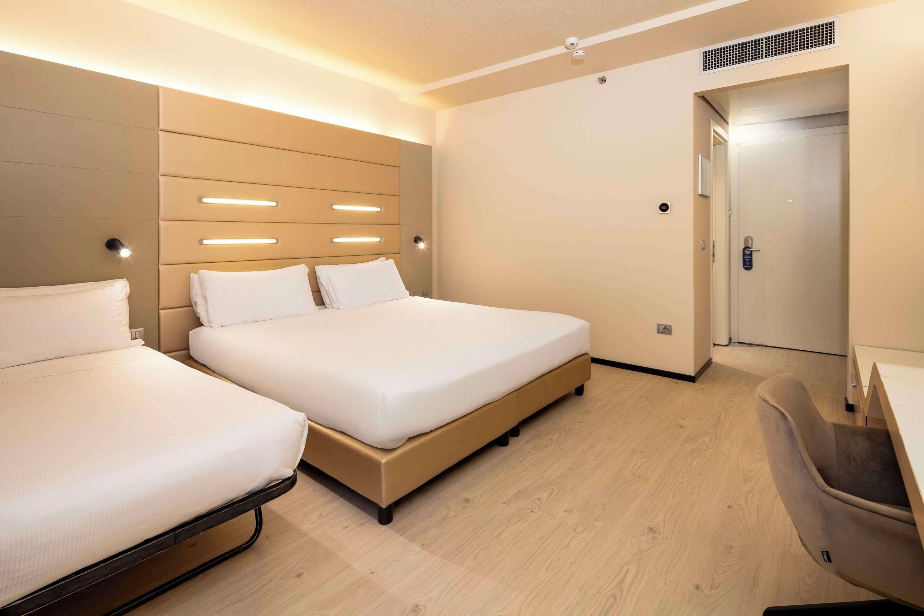 Habitación de hotel con dos camas, un escritorio y una silla.
