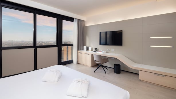 A modern hotel room with a large bed, a desk, a flat-screen TV, and a city view. - Best Western Plus Tower Hotel Bologna (Bologna)
