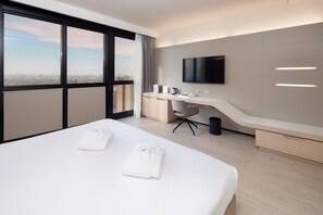 Habitación de hotel moderna con una cama grande, un escritorio, un televisor de pantalla plana y vistas a la ciudad.