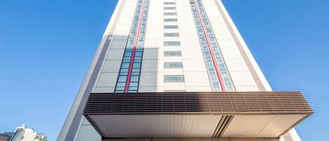 A tall hotel building with a clear sky. The hotel's name is 'Best Western Plus' and it is located in Bologna.