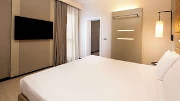 Una habitación de hotel moderna con una cama grande, un televisor de pantalla plana en la pared, una mesita de noche y un espejo.