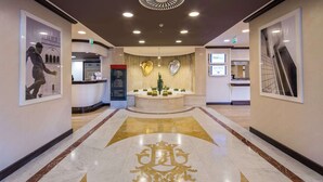 A hotel lobby with a reception desk, a large emblem on the floor, and framed artwork on the walls. - Best Western Plus Tower Hotel Bologna (Bologna)