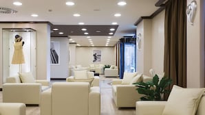 A modern hotel lobby with a central seating area, a staircase, and a view of the city. - Best Western Plus Tower Hotel Bologna (Bologna)
