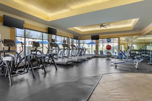 Un gimnasio con cintas de correr, elípticas y equipo de pesas.