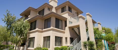 A multi-story building with a beige facade, large windows, and a central staircase.