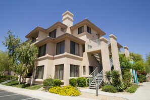 Un edificio de varios pisos con fachada color beige, ventanas grandes y una escalera central.