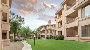 A residential building with multiple balconies, a well-maintained lawn, and a clear sky.