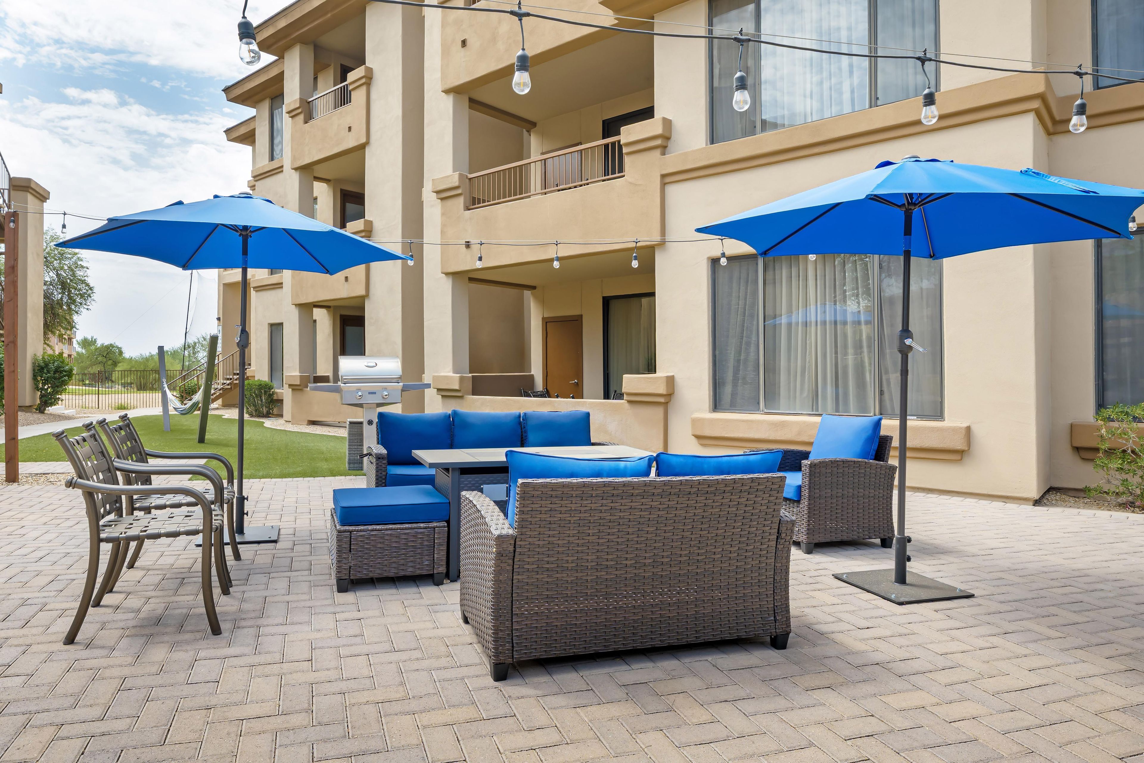 A patio area with outdoor furniture, including sofas and chairs, and a barbecue grill.
