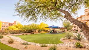 A well-maintained outdoor area with a playground, a covered seating area, and a variety of landscaped plants.