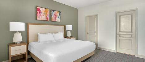A hotel room with a bed, two bedside tables, a ceiling fan, and two abstract paintings on the wall.