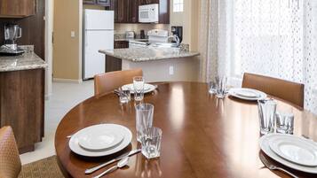 A dining area with a wooden table set for four, including plates, cutlery, and glasses.