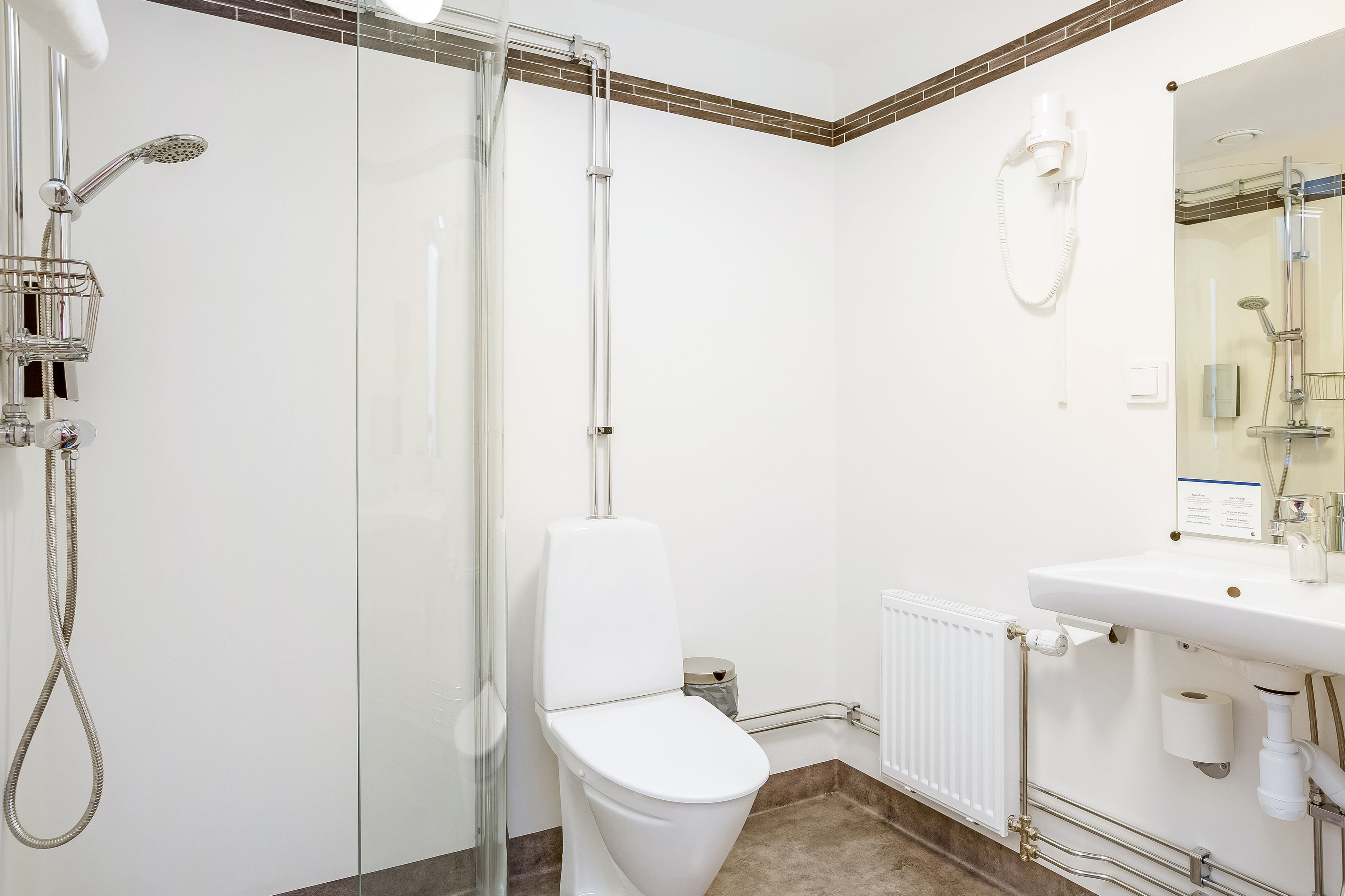 Un baño moderno con ducha de vidrio, inodoro blanco y lavamanos con espejo.