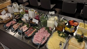 Un buffet proposant une variété de plats, notamment des viandes, des fromages et des salades.