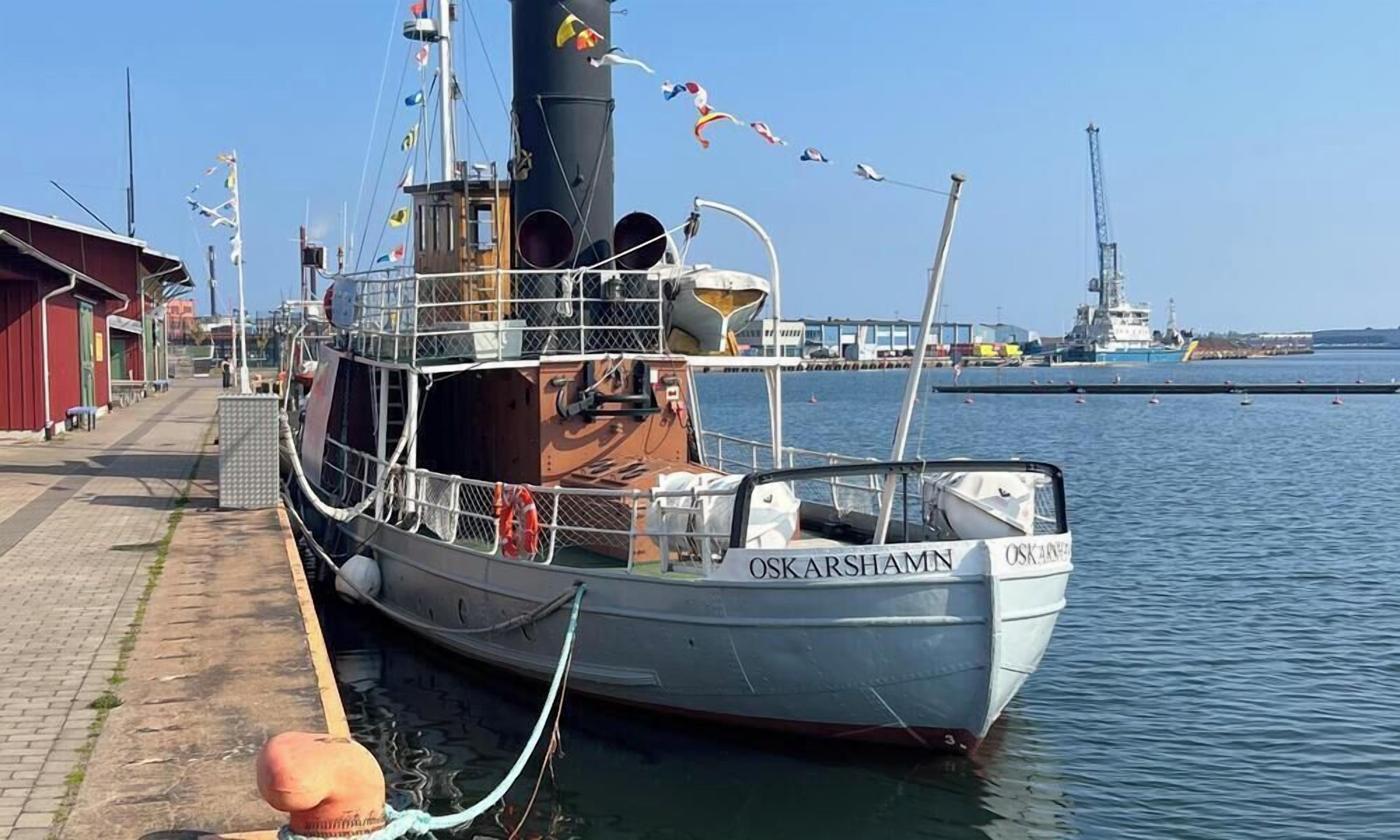 A docked boat named "OSKARSHAMN" with a metal railing and a cabin structure.