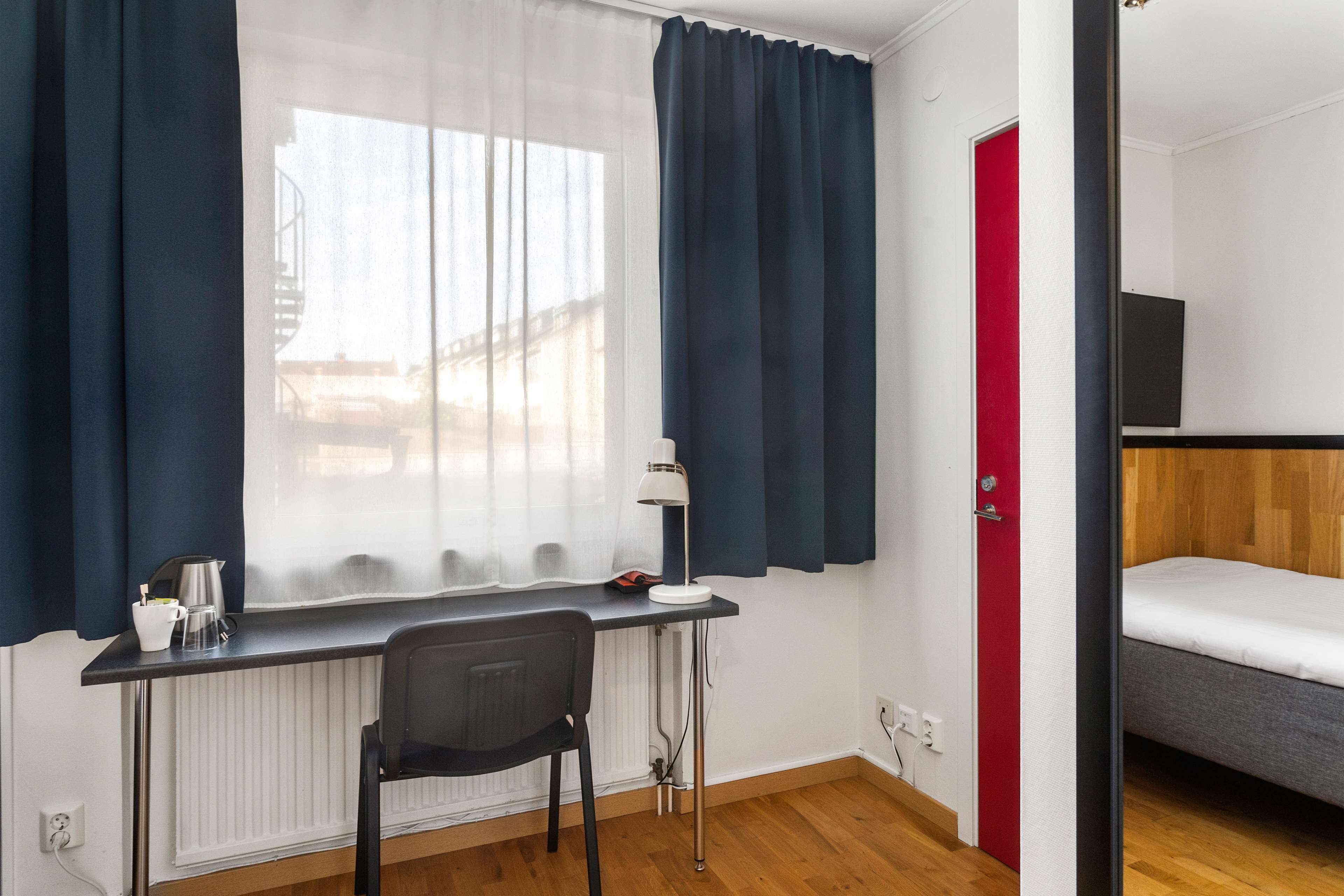 A room with a desk, chair, and a bed.