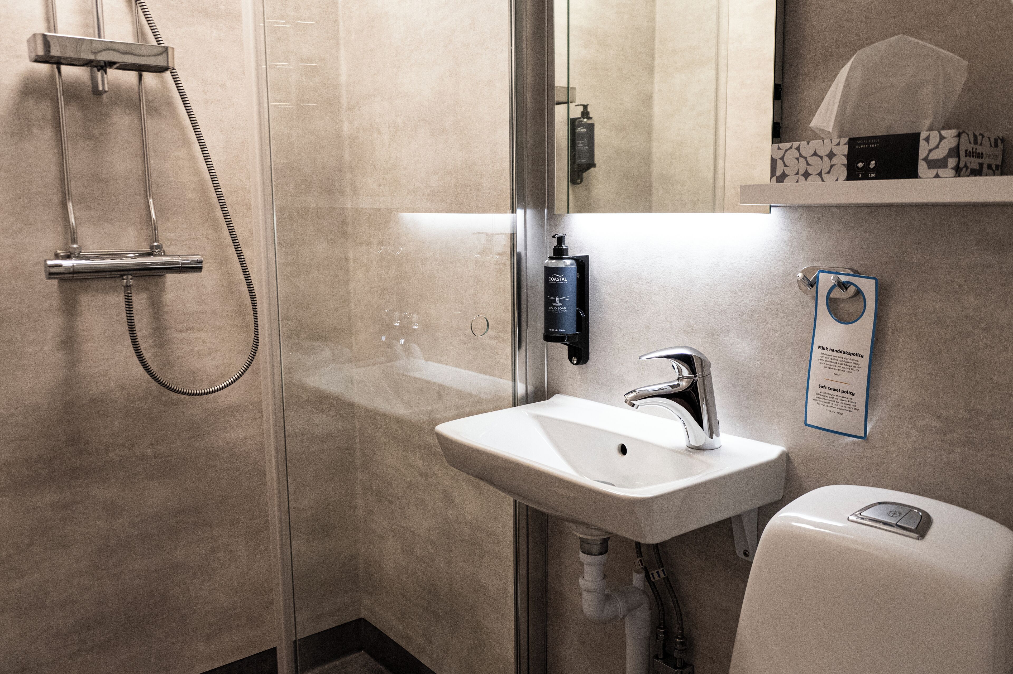 Un baño moderno con ducha envuelta en vidrio, un lavabo blanco y un inodoro.