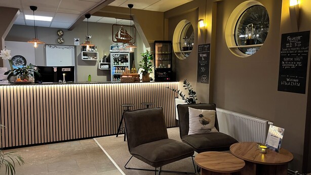 Eine gemütliche Bar mit einer Theke, Sitzgelegenheiten und dekorativen Elementen wie Pflanzen und Wandbildern.