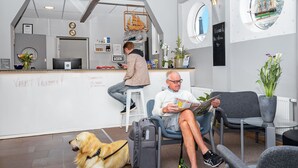 Ein Empfangsbereich mit einem Schreibtisch, Stühlen, einem Hund und einem Mann, der eine Zeitschrift liest.