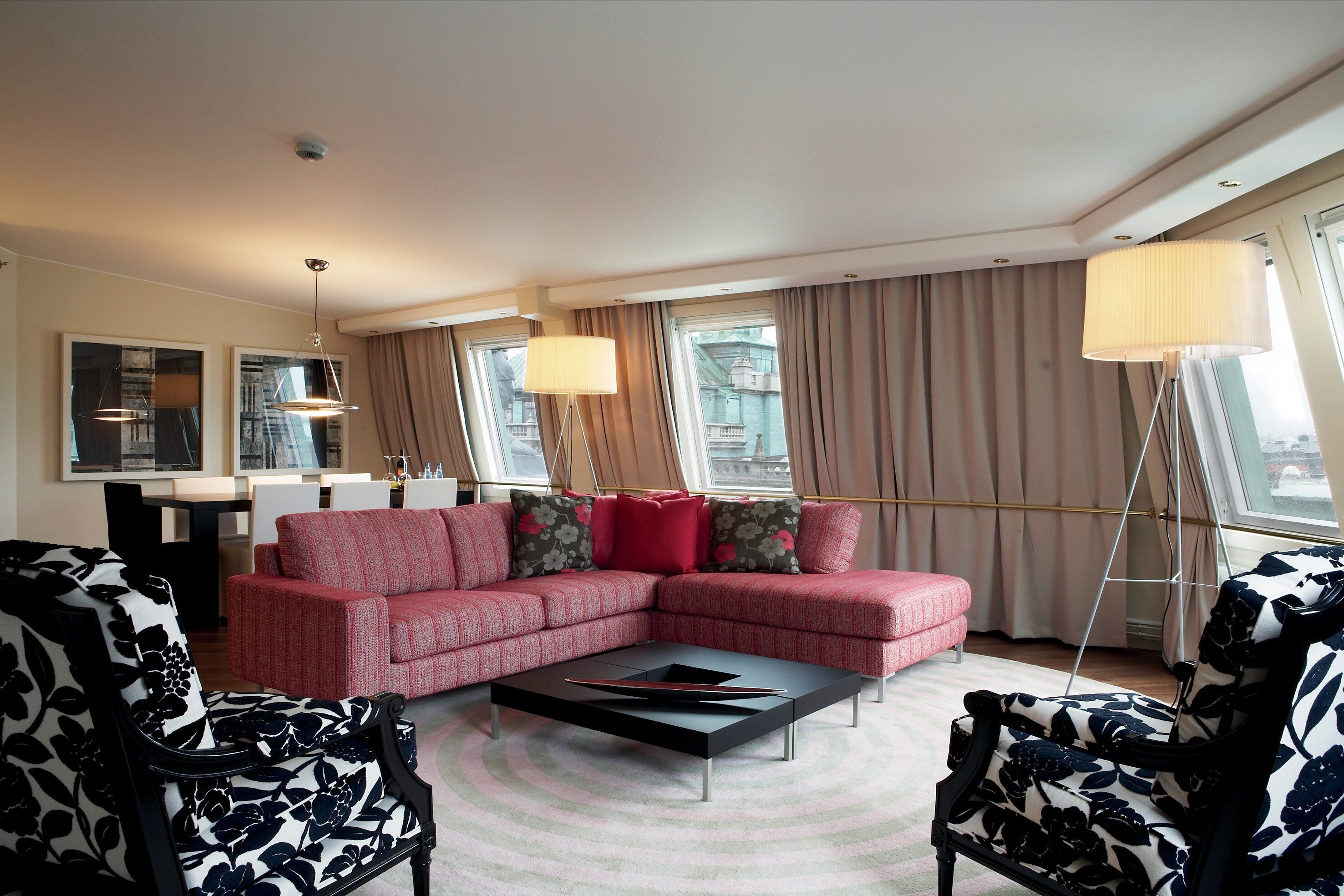 A modern living room with a sectional sofa, two armchairs, a coffee table, and a dining area with a table and chairs.