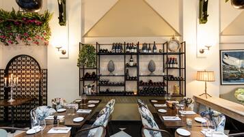 A restaurant with a wine cellar, wooden tables, and chairs.