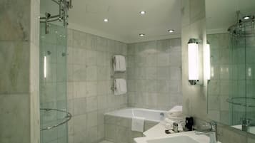 Un baño moderno con ducha de vidrio, bañera independiente y un amplio tocador con espejo.