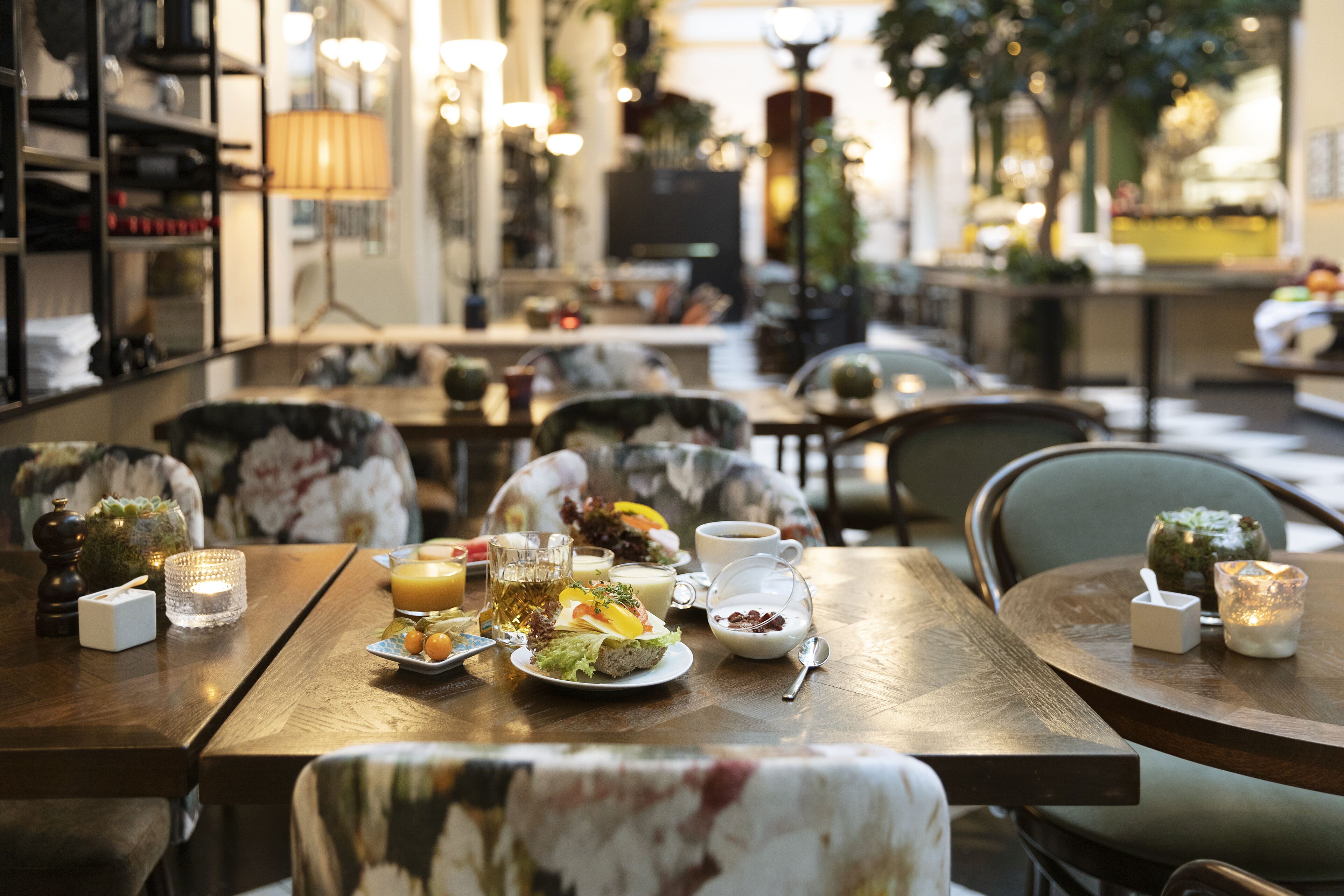 Comedor con mesas dispuestas para una comida, incluyendo platos de comida, tazas y vasos.