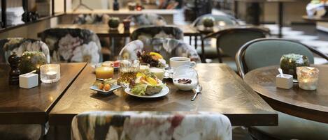 A dining area with tables set for a meal, including plates of food, cups, and glasses.