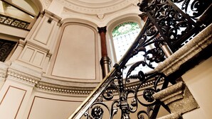 Eine prächtige Treppe mit aufwendiger Metallgeländerung und einem Kronleuchter.
