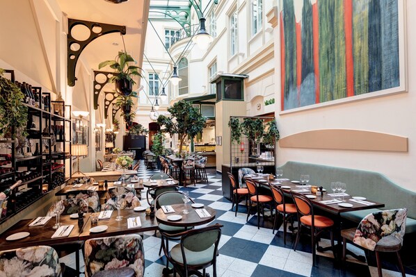 Un restaurante con suelo a cuadros, mesas dispuestas para comer y diferentes tipos de sillas.