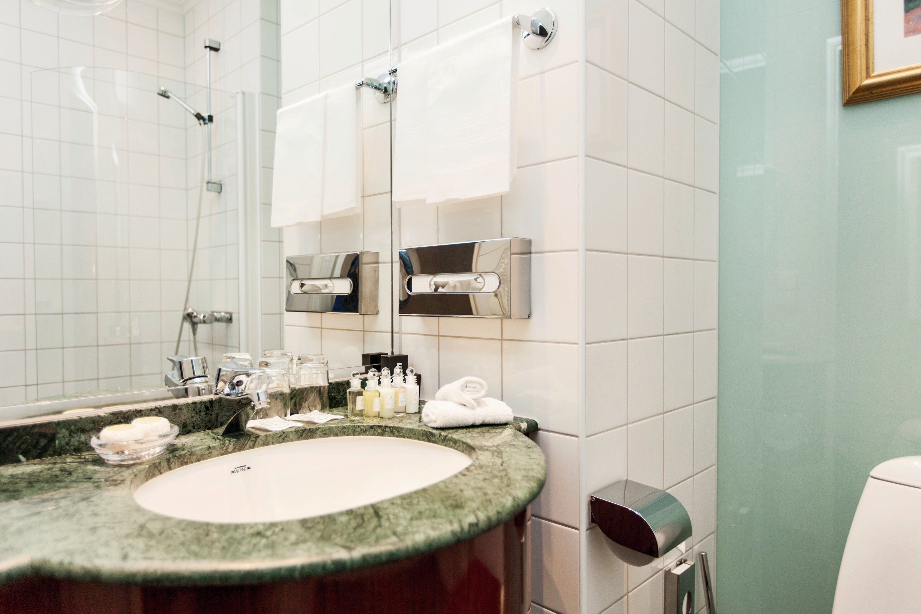 A modern bathroom with a granite countertop, a sink, a mirror, and a glass shower enclosure.