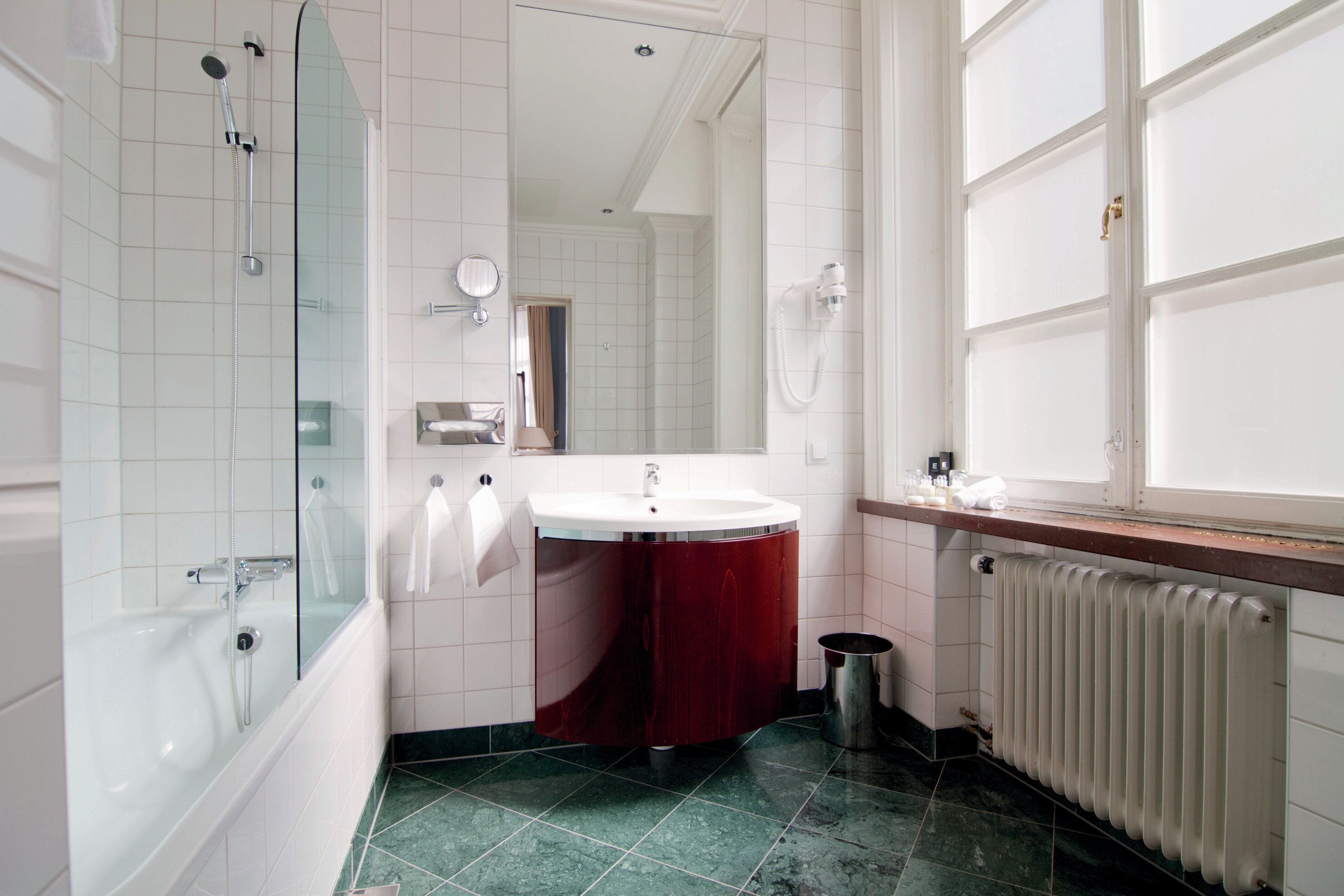 A bathroom with a bathtub, a sink, a mirror, and a window.