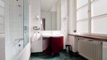 A bathroom with a bathtub, a sink, a mirror, and a window.
