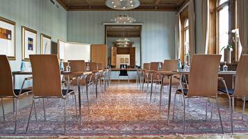 Un salón de conferencias con alfombra estampada, sillas de madera y una mesa grande.