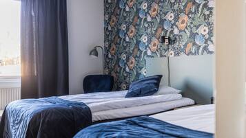 A bedroom with a bed, a chair, and a wall with floral wallpaper.
