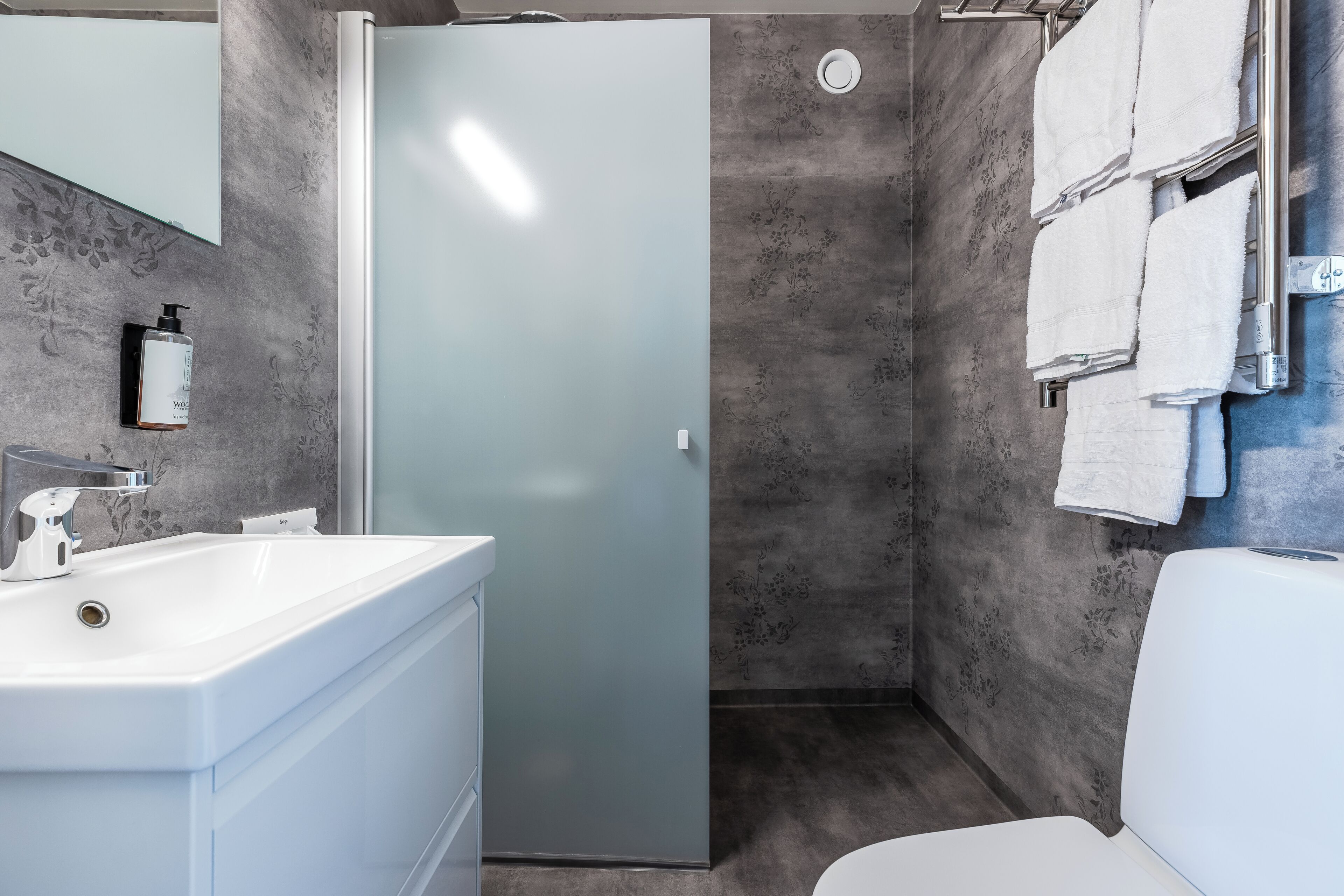 A modern bathroom with a white sink, mirror, and toilet.