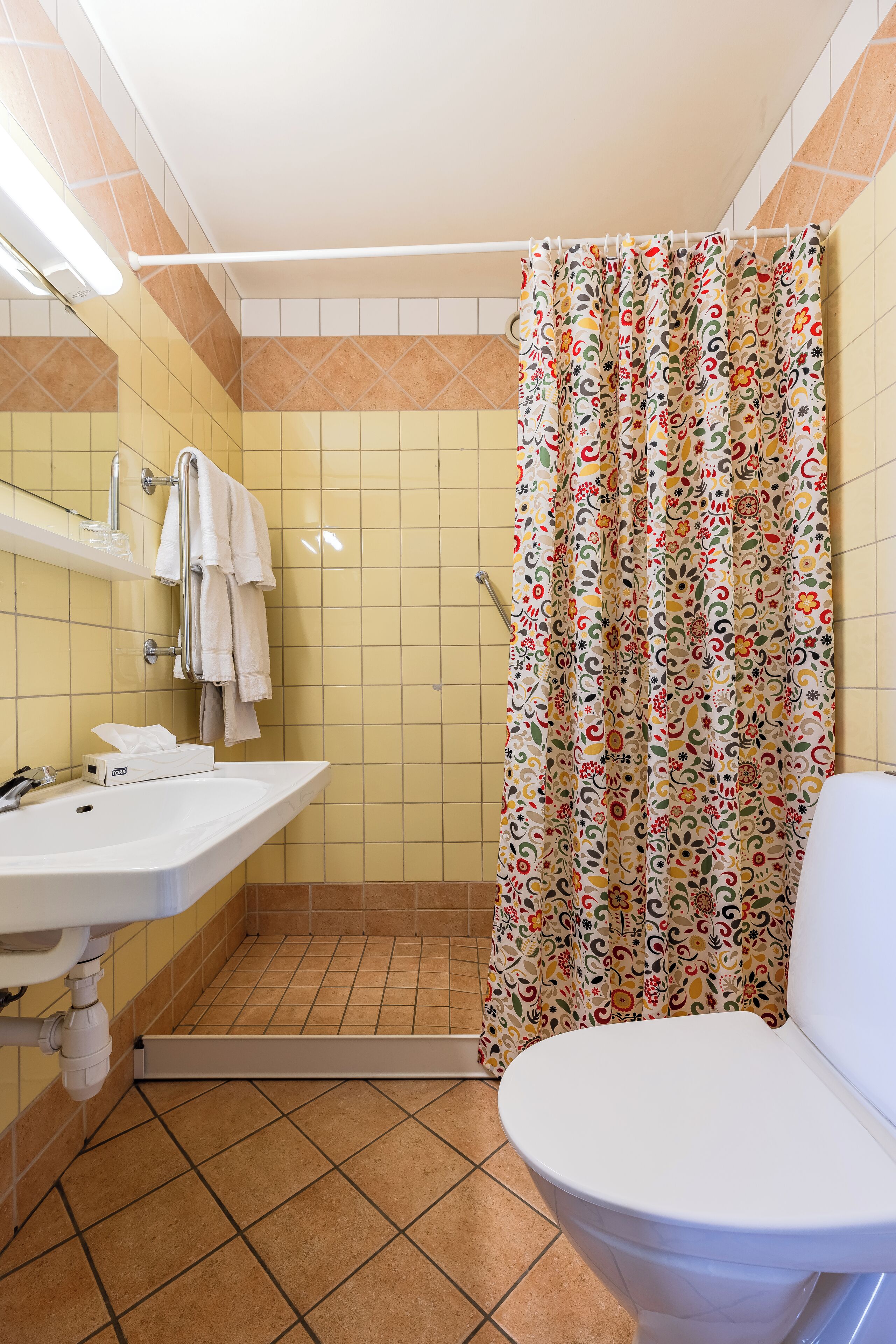 A bathroom with a shower curtain, a sink, and a toilet.