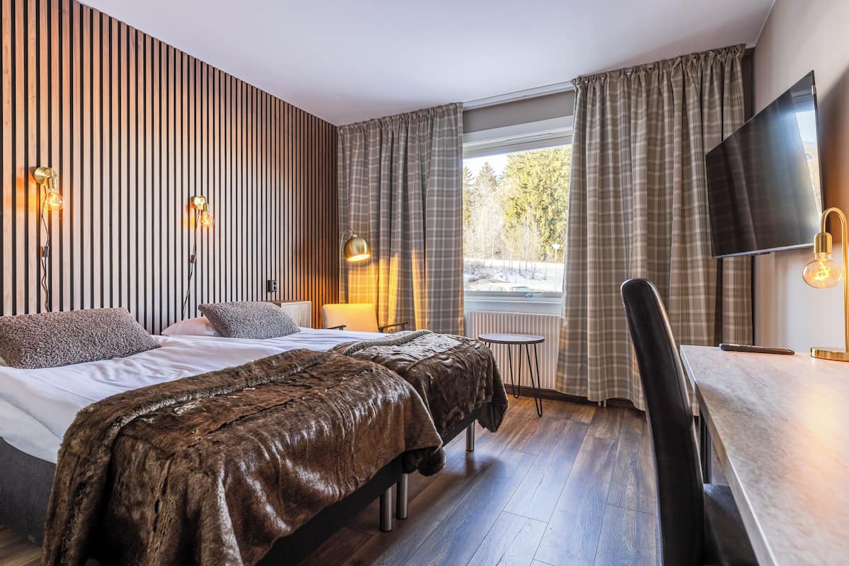 Una habitación de hotel moderna con una cama grande, un escritorio y un televisor.