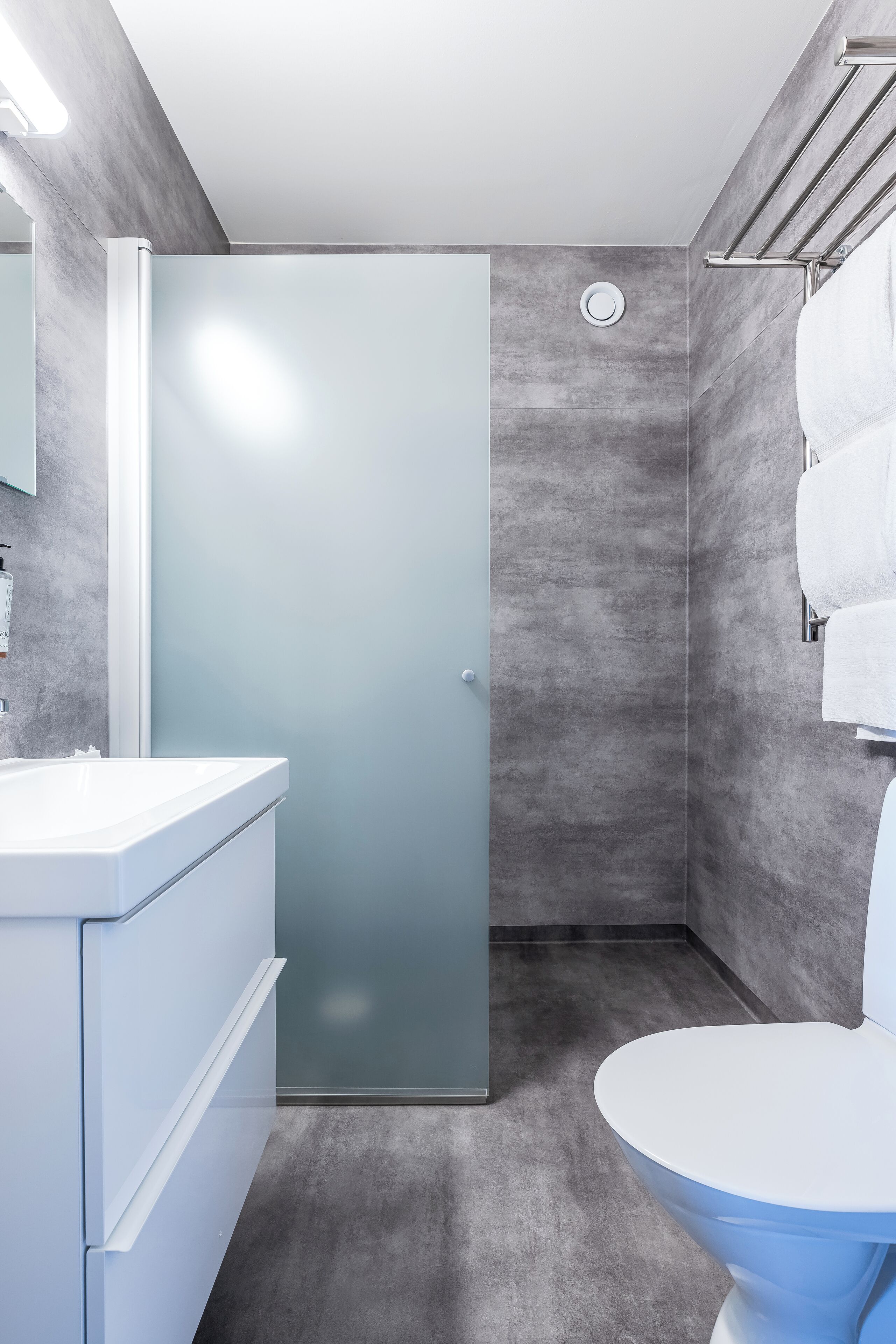 A modern bathroom with a glass shower door, a white sink, and a toilet.