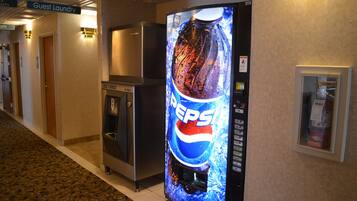 A hallway with a vending machine, a refrigerator, and a sign for guest laundry.